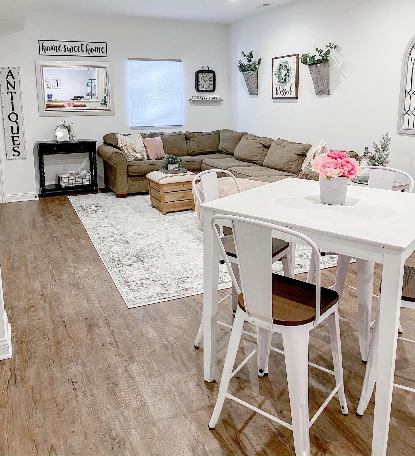 Spacious country-style living room with sectional sofa, white dining set, and rustic decor.